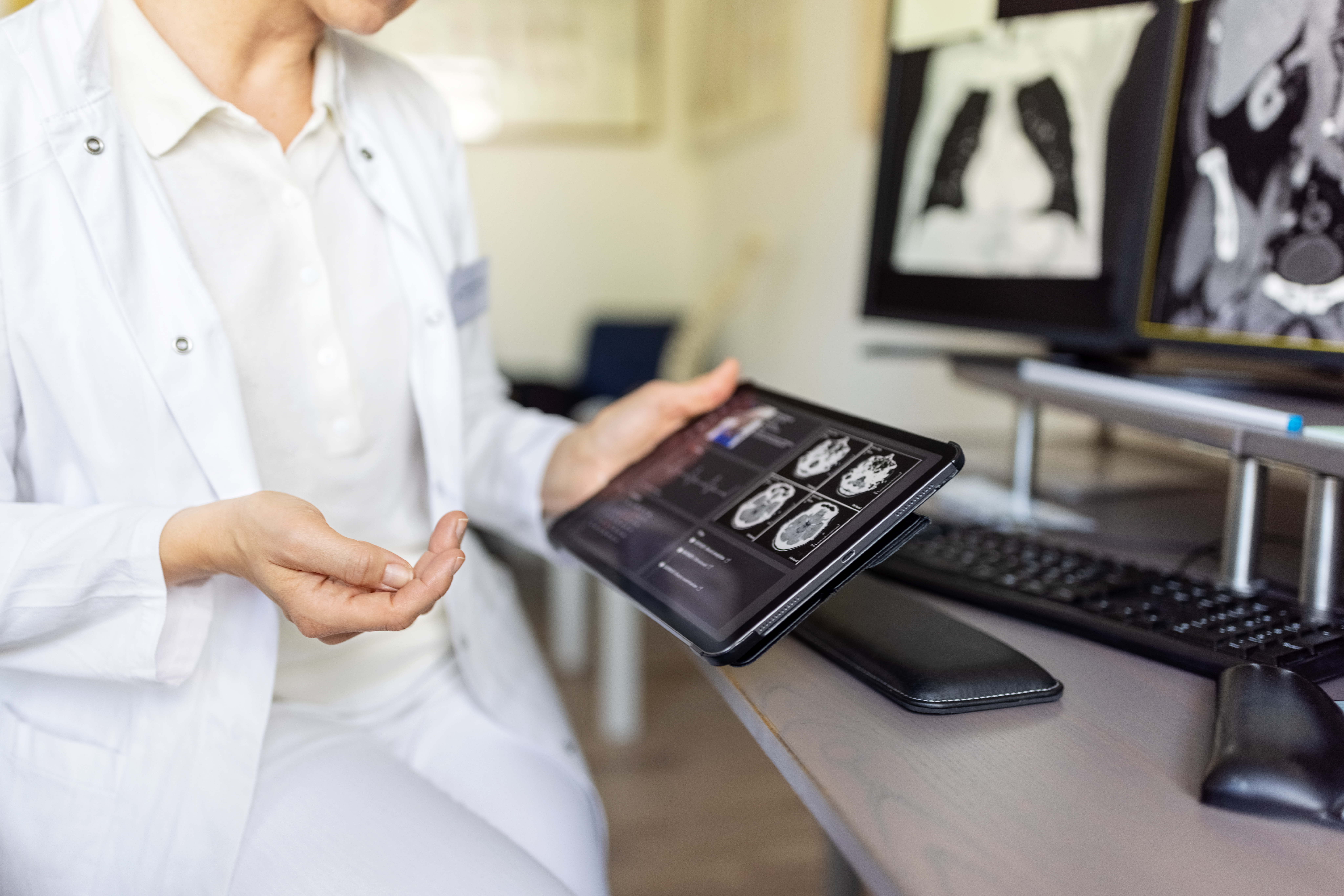 Woman doctor examining MRI scan reports of patient on digital tablet