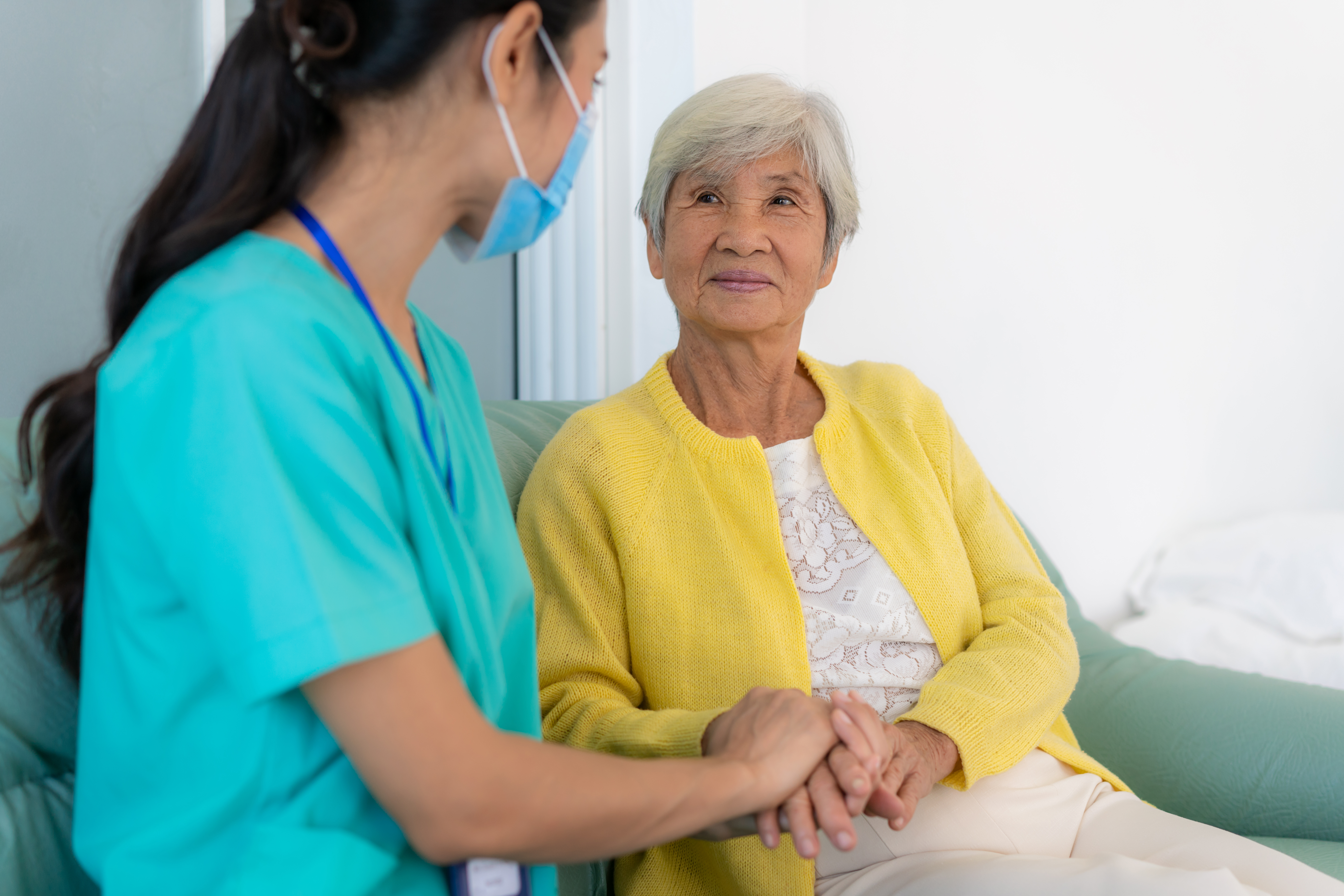 Caring smiling young Asian nurse taking care supporting happy elder grandma patient, female doctor caregiver provide medical services helping old woman at homecare medical visit, seniors healthcare concept